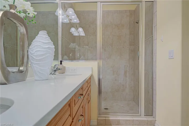 Bathroom featuring double vanity and a shower stall