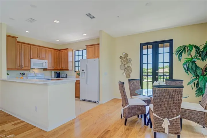 Kitchen with white appliances, light countertops, brown cabinets, recessed lighting, and light wood-style flooring