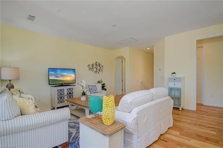 Living room with arched walkways and wood finished floors