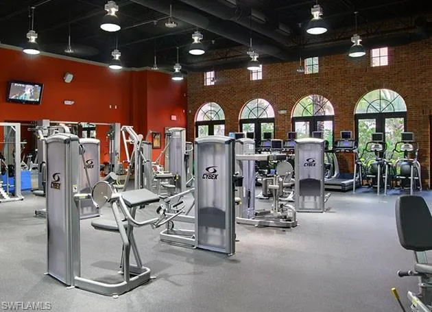 Gym featuring a high ceiling and brick wall