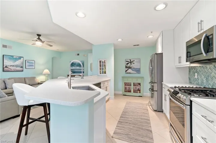 Kitchen featuring decorative backsplash, white cabinets, a breakfast bar, and appliances with stainless steel appliances