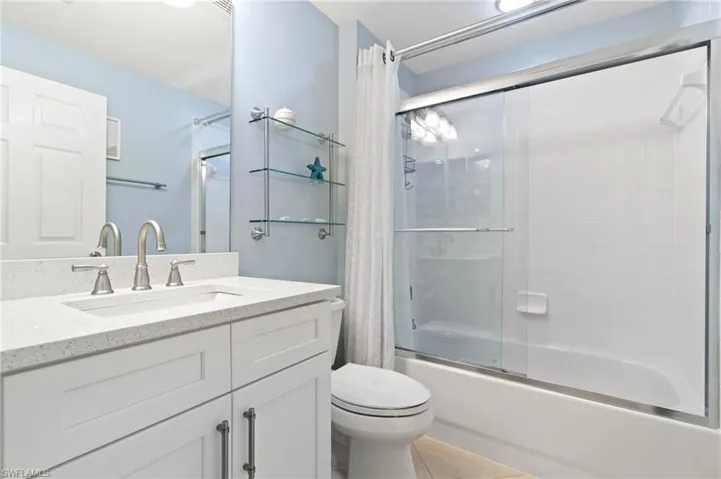 Full bathroom with vanity, toilet, tile patterned floors, and shower / bathtub combination with curtain