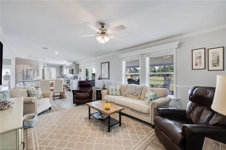 Living area featuring crown molding, plenty of natural light, a ceiling fan, and light wood-type flooring