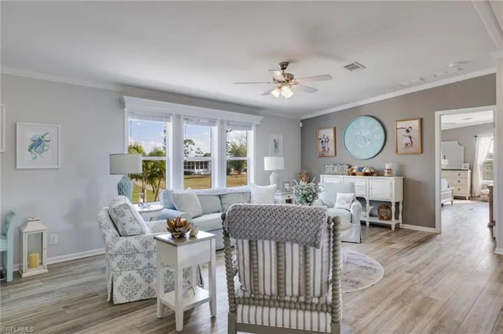 Living room with crown molding, a ceiling fan, and wood finished floors
