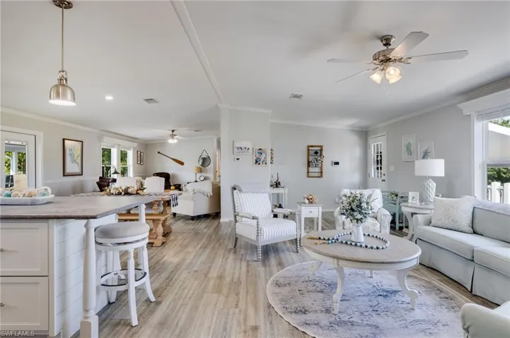 Living area featuring ceiling fan, light wood finished floors, and crown molding