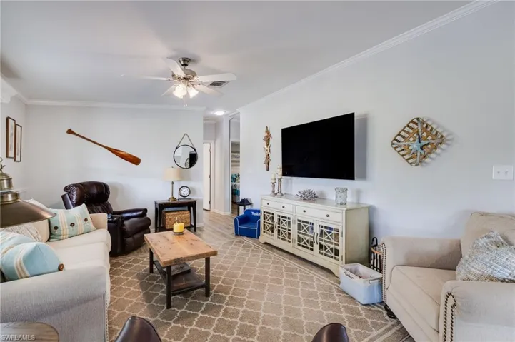 Living area with crown molding, a ceiling fan, and wood finished floors
