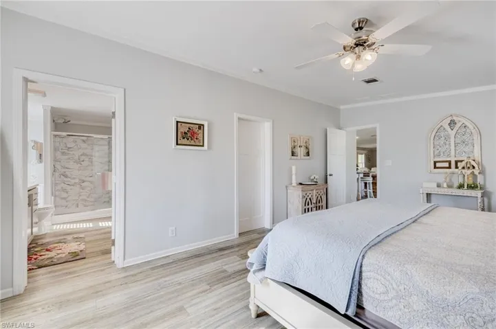 Bedroom featuring crown molding, a ceiling fan, light wood-style flooring, and ensuite bath