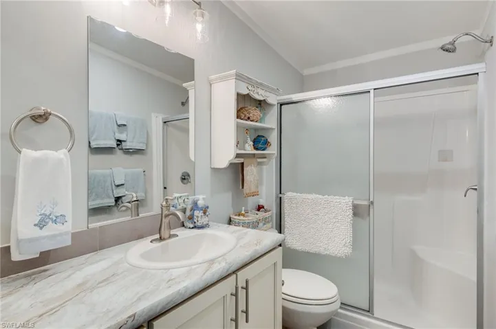 Full bathroom featuring crown molding, a stall shower, and vanity