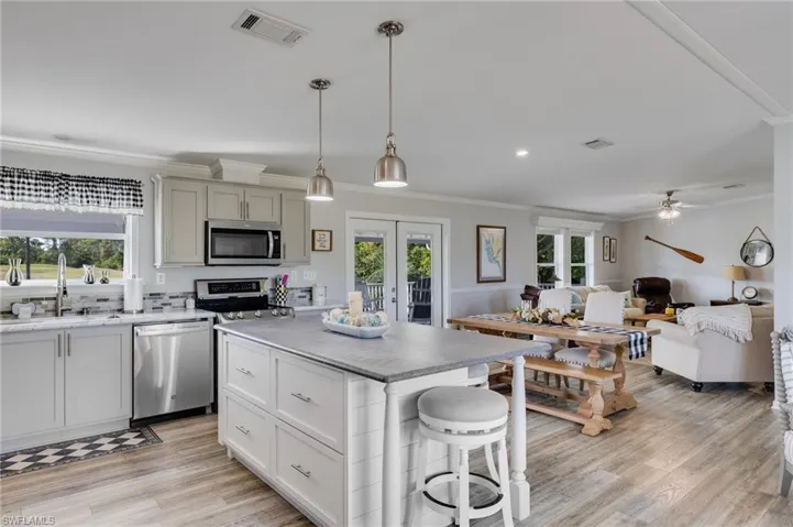 Kitchen featuring open floor plan, a kitchen breakfast bar, hanging light fixtures, appliances with stainless steel finishes, and healthy amount of natural light
