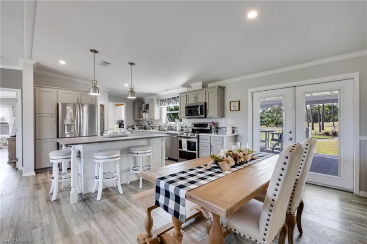 Dining space featuring vaulted ceiling, crown molding, french doors, light wood-style floors, and recessed lighting