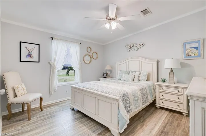 Bedroom featuring crown molding, light wood-style floors, and ceiling fan