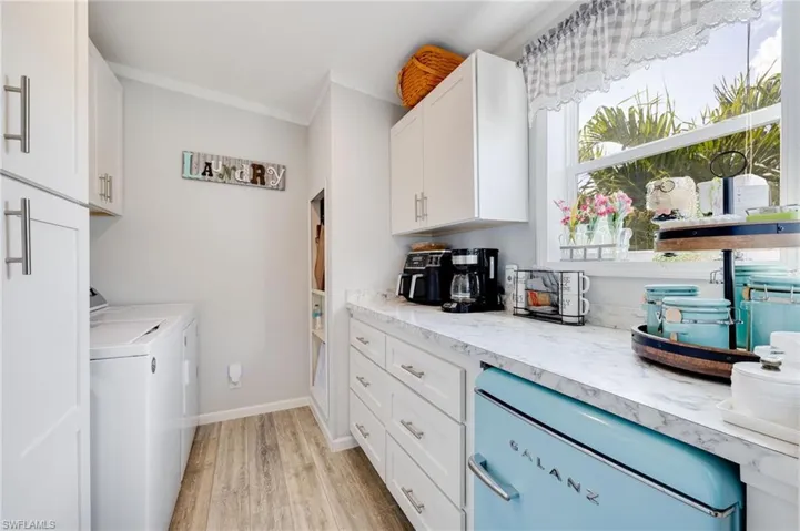 Laundry area with crown molding, light wood-style flooring, and washing machine and dryer