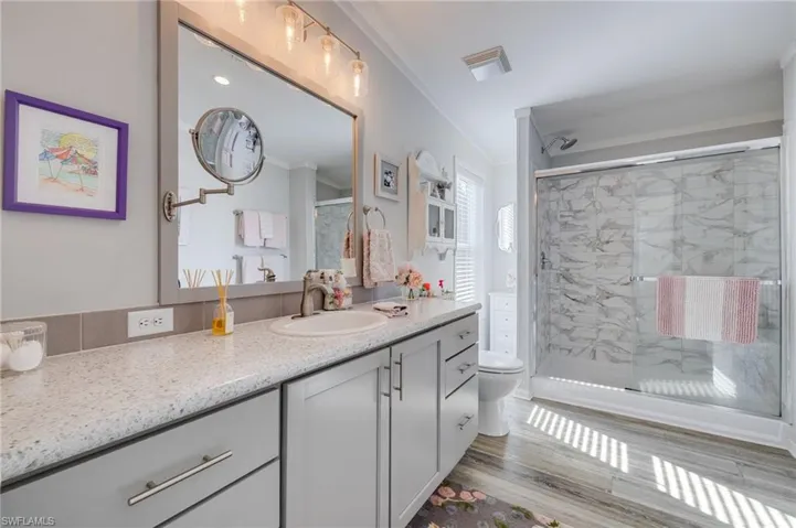 Bathroom with vanity, a shower stall, crown molding, and light wood finished floors