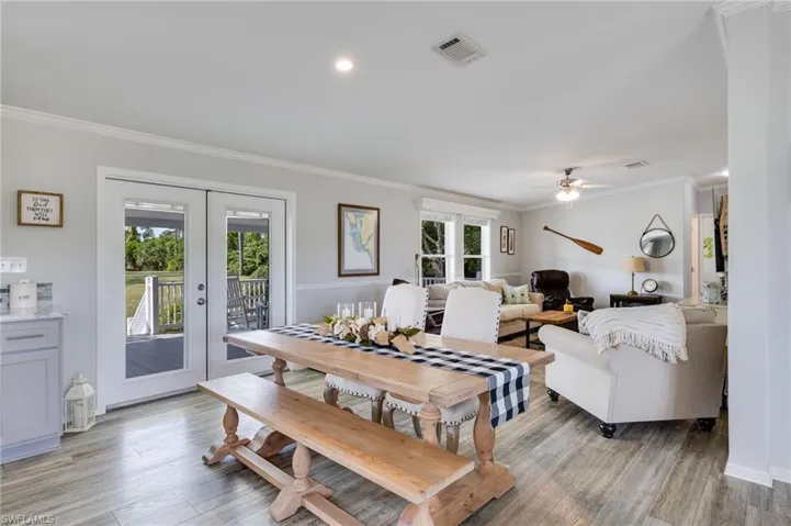 Dining area with crown molding, light wood finished floors, french doors, and ceiling fan