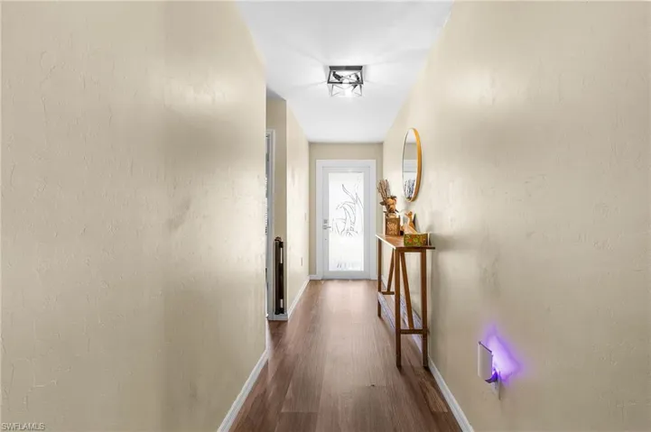 Hallway with dark wood-style floors and a textured wall