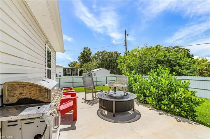 Fenced backyard featuring an outdoor fire pit, a patio area, and grilling area