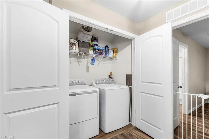 Washroom with dark wood-type flooring and washing machine and dryer