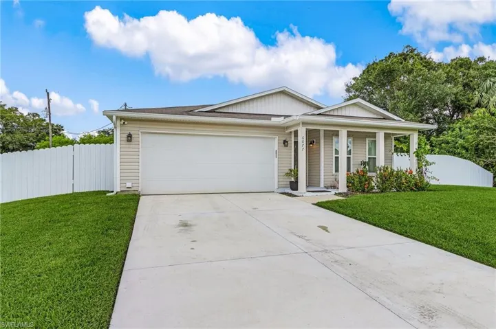 Ranch-style house with covered porch, driveway, a garage, and board and batten siding