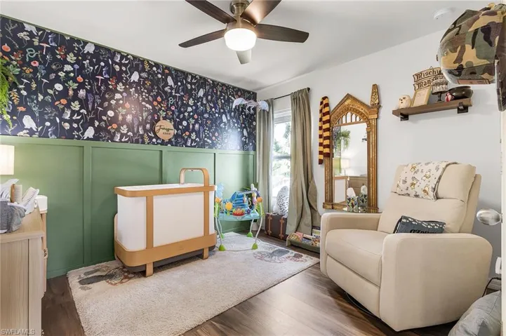 Sitting room featuring a decorative wall, wood finished floors, and ceiling fan