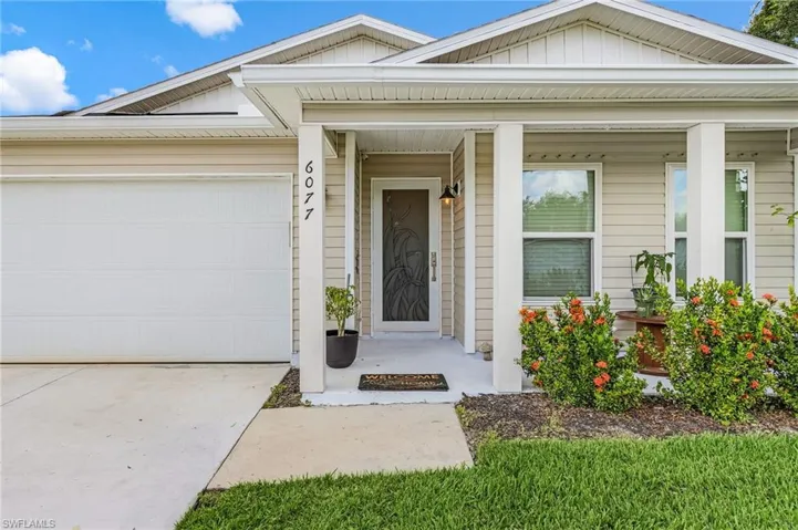 Entrance to property with board and batten siding, a porch, concrete driveway, and a garage
