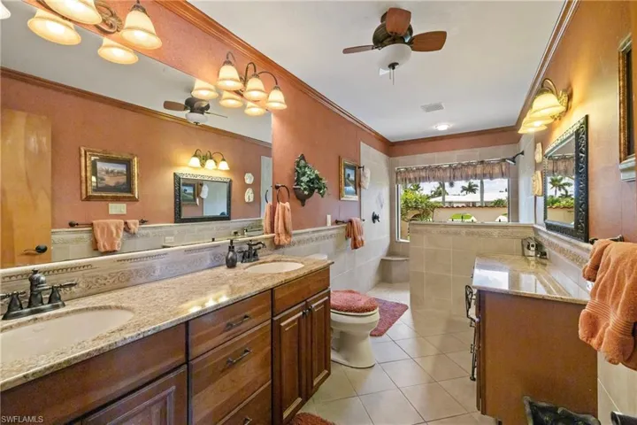 Bathroom with tile patterned floors, ceiling fan, toilet, and vanity