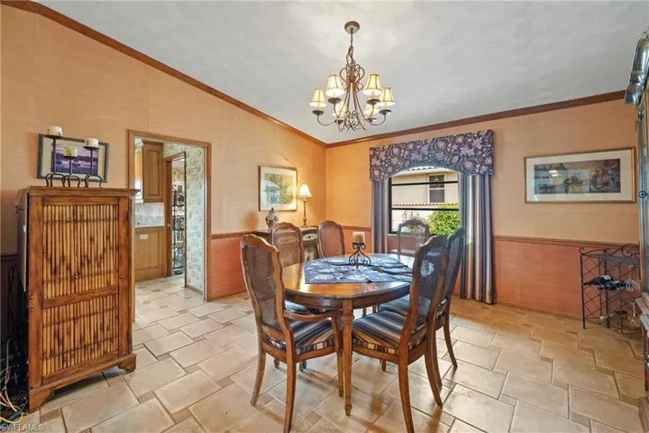 Dining room featuring ornamental molding, wood walls, and an inviting chandelier