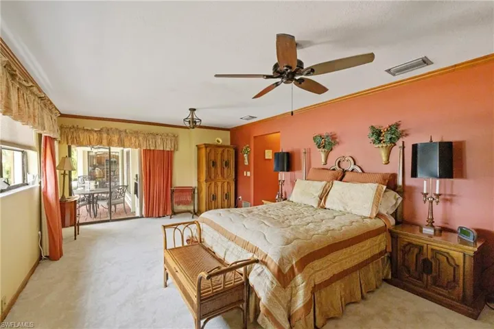 Carpeted bedroom with ceiling fan and ornamental molding