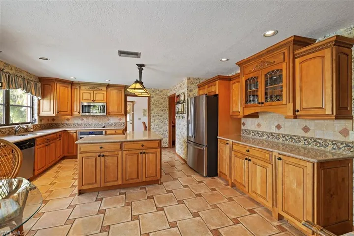 Kitchen featuring hanging light fixtures, a kitchen island, stainless steel appliances, and a textured ceiling