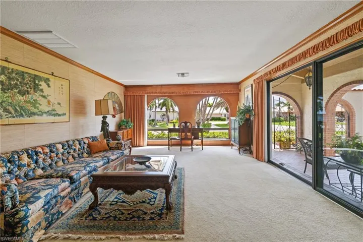 Carpeted living room featuring a textured ceiling and ornamental molding