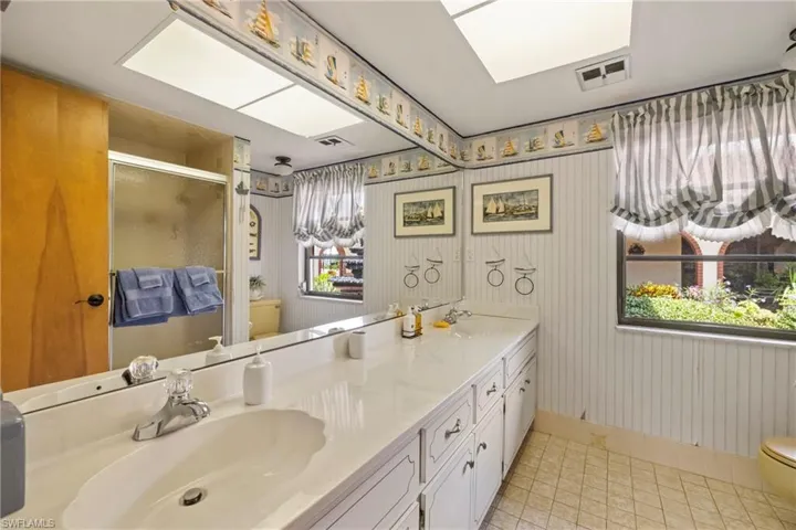 Bathroom with an enclosed shower, tile patterned flooring, toilet, and vanity