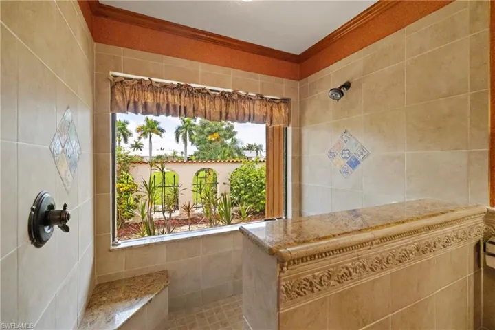 Bathroom featuring walk in shower, ornamental molding, and a healthy amount of sunlight