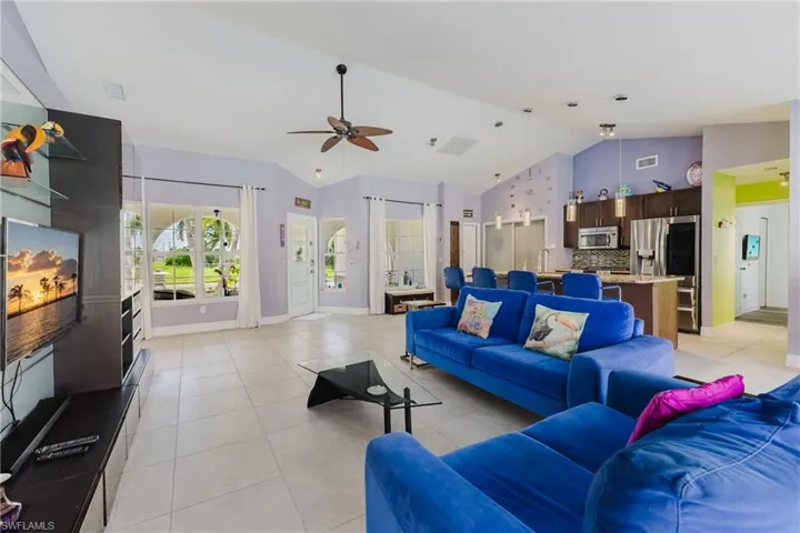 Living area featuring light tile patterned floors, high vaulted ceiling, and ceiling fan
