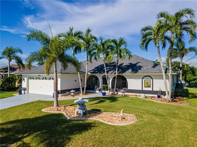 View of front of house with a shingled roof, stucco siding, an attached garage, driveway, and a front yard
