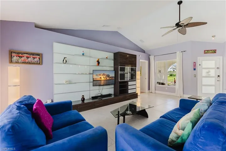 Tiled living room featuring vaulted ceiling and a ceiling fan