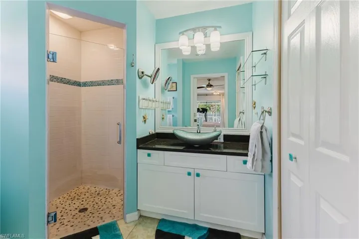 Bathroom with a shower stall, vanity, ceiling fan, and light tile patterned flooring