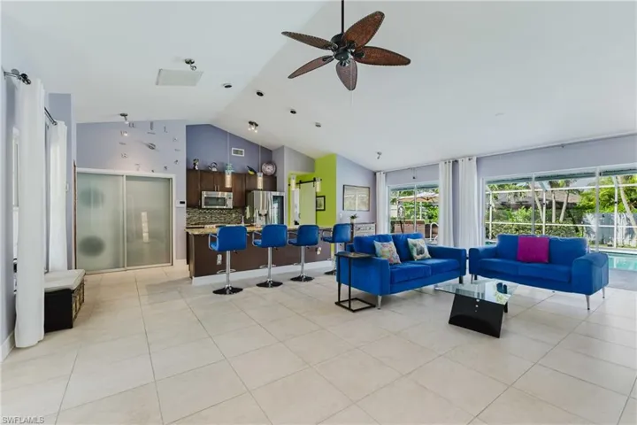 Living area featuring high vaulted ceiling, light tile patterned floors, and ceiling fan