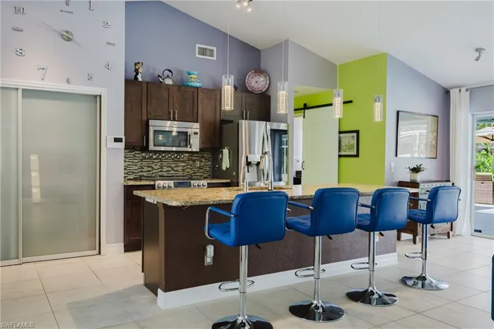 Kitchen featuring dark brown cabinetry, a barn door, a breakfast bar area, backsplash, and light tile patterned flooring