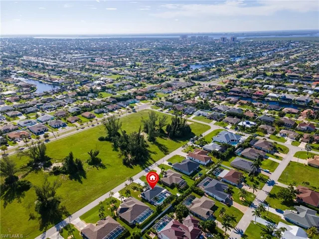 Aerial view of property and surrounding area with nearby suburban area and a large body of water