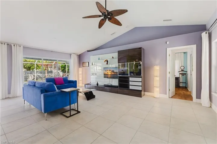 Living area with lofted ceiling, ceiling fan, and light tile patterned floors
