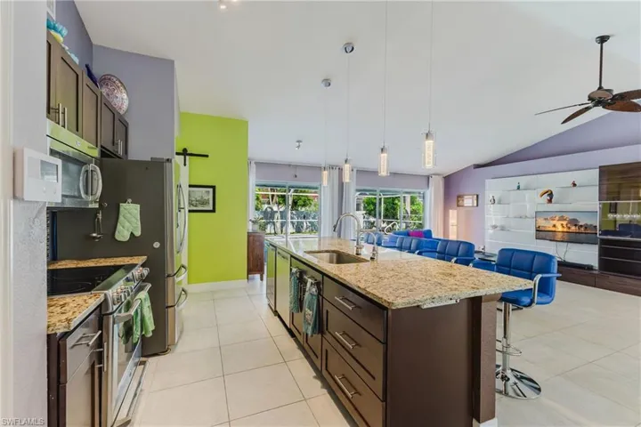 Kitchen featuring dark brown cabinetry, light tile patterned flooring, a breakfast bar, appliances with stainless steel finishes, and lofted ceiling