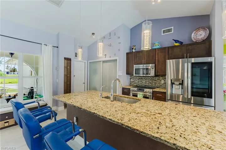 Kitchen featuring dark brown cabinets, stainless steel appliances, high vaulted ceiling, tasteful backsplash, and pendant lighting