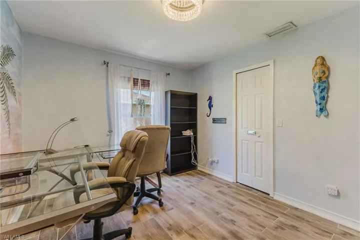 Home office with light wood-style tile floors and a chandelier