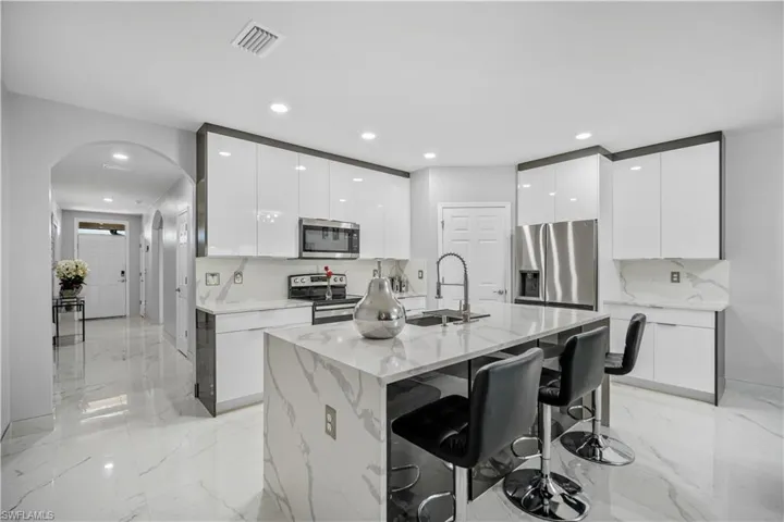 Kitchen featuring a center island with sink, white cabinets, sink, and appliances with stainless steel finishes