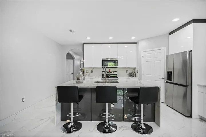 Kitchen with a kitchen breakfast bar, sink, white cabinets, and appliances with stainless steel finishes