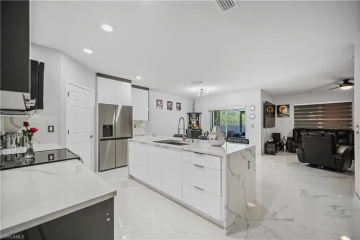 Kitchen with ceiling fan, sink, light tile flooring, and stainless steel refrigerator with ice dispenser