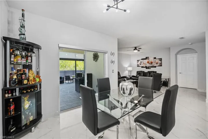 Dining room with ceiling fan with notable chandelier and light tile flooring