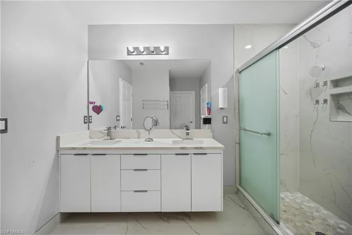 Bathroom with tile floors, walk in shower, double sink, and vanity with extensive cabinet space