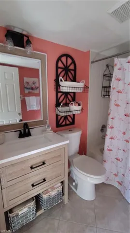 Bathroom featuring vanity, shower / bath combo with shower curtain, and light tile patterned floors