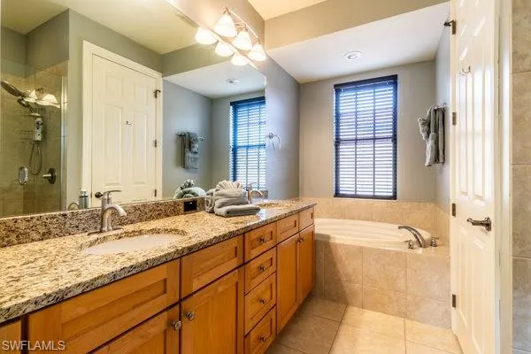 Bathroom with tile patterned floors, vanity, and shower with separate bathtub