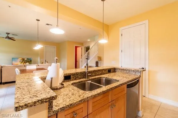 Kitchen with stainless steel dishwasher, pendant lighting, sink, and light tile patterned flooring